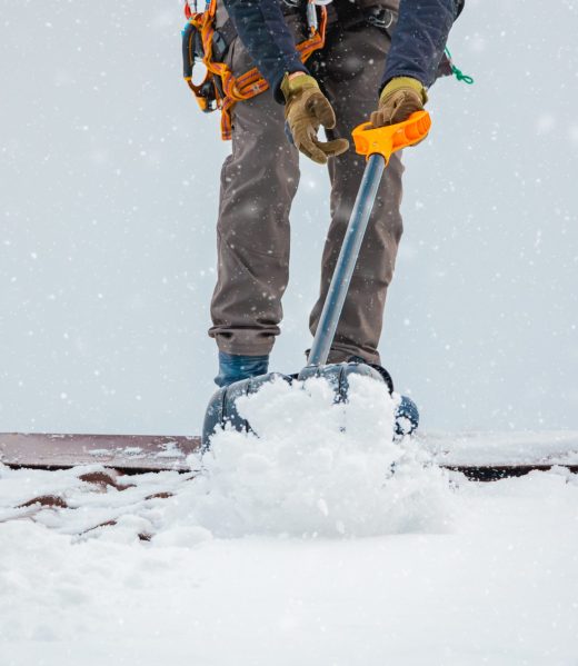 Communal services worker industrial climber removes snow from the building roof in winter. Cleaning city streets, roads and buillding roofs after snow storm in Moscow, Russia